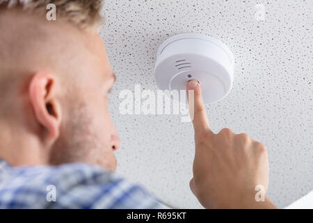 Person's Hand Installing Smoke Detector On Ceiling Stock Photo