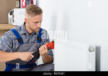 Male Plumber Fixing Thermostat Using Wrench Stock Photo