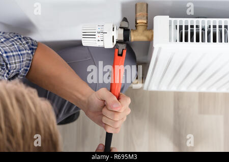 Male Plumber Fixing Thermostat Using Wrench Stock Photo