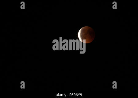 Moon in the starry sky with a blood red color as a result of a lunar eclipse through the earth. Stock Photo