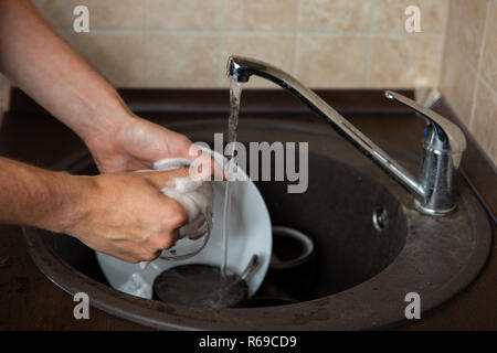 Image of side of man's hands washing transparent mug in sink Stock Photo