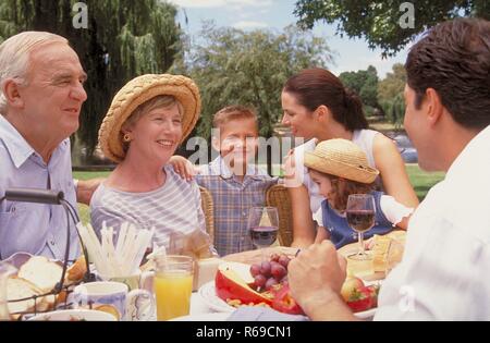 Parkszene, Portrait, 3 Generationen einer Familie geniessen einen Sommertag im Gruenen bei einem Picknick Stock Photo
