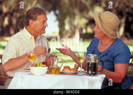 Halbfigur, Seniorenpaar Mitte 60 sitzt im Sommer im Garten beim Fruehstueck Stock Photo