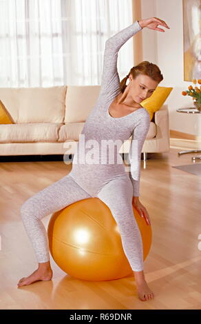 Portrait, schwangere Frau sitzt  auf einem gelben Ball und macht Gymnastik Stock Photo