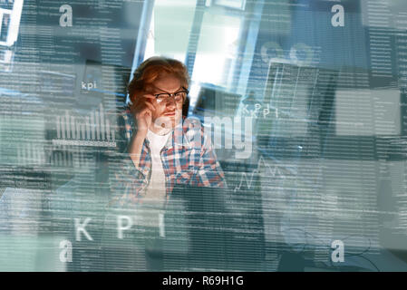 Young concentrated computer developer writing new code in glasses Stock Photo