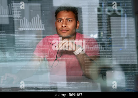Young spectacled concentrated indian data analyst using big data Stock Photo