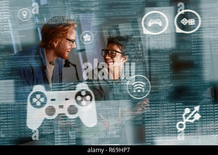 Young indian woman game developer and red haired man are laughting about idea Stock Photo