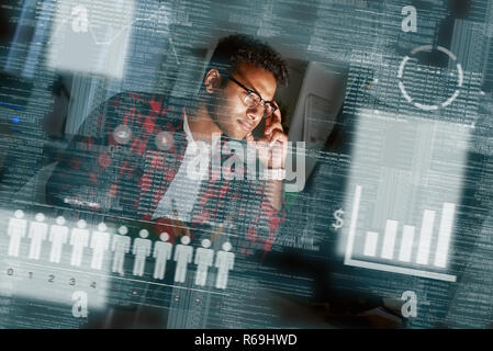Young concentrated indian SEO specialist looking over advertising conversion Stock Photo