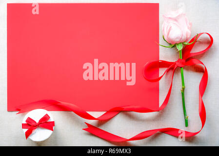 Pink rose with a gift and red paper sheet Stock Photo