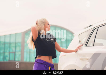 Cheerful young female driver hugging her new car. Stock Photo