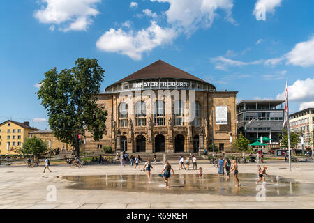 Playing children at the fountain in front of the city theater, Freiburg im Breisgau, Black Forest, Baden-Württemberg, Germany Stock Photo