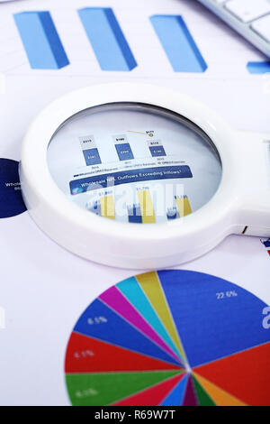 Close up of chart paper and magnifying glass. Stock Photo