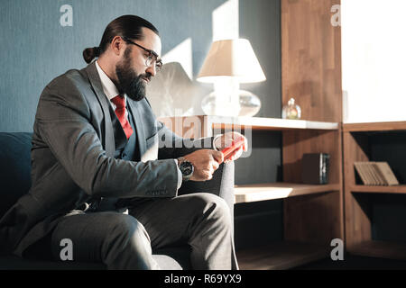 Serious bearded businessman reading e-mails on his red phone Stock Photo