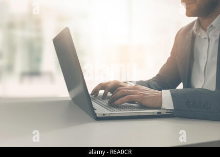young man typing on laptop in modern bright coworking office Stock Photo