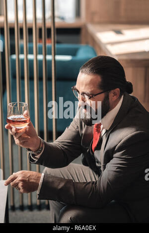 Bearded man wearing glasses and business attire drinking cognac Stock Photo