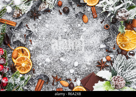 Holiday baking background for baking Christmas cookies with cutters and spices on grey concrete table with snow. Holiday baking or cooking ingredients Stock Photo