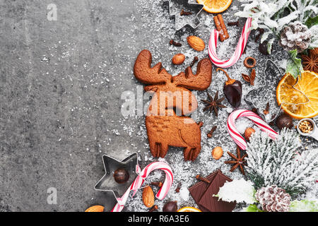 Holiday baking background. Baking Christmas gingerbread cookies with cutters and spices on grey concrete table with snow. Holiday baking or cooking in Stock Photo