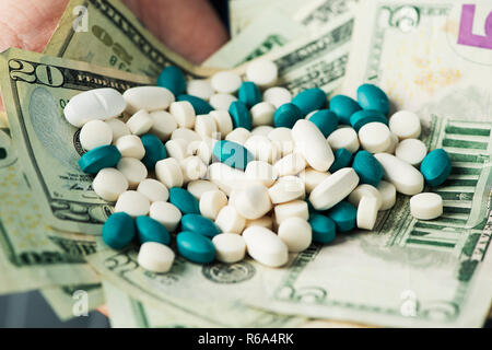 closeup of a young caucasian businessman with a pile of dollar bills and pills of different colors in his hands Stock Photo