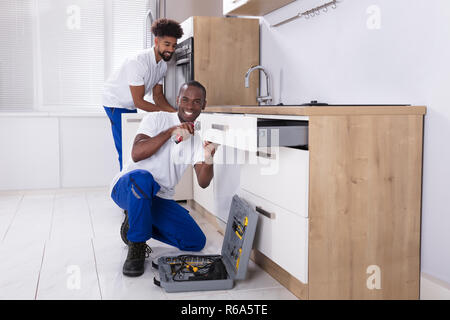 Repairmen Fixing The Wooden Cabinet In The Kitchen Stock Photo