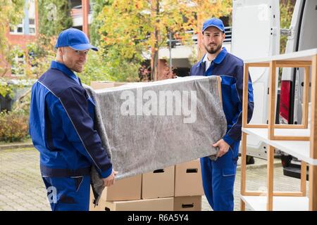 Two Male Worker Unloading Furniture From Truck Stock Photo