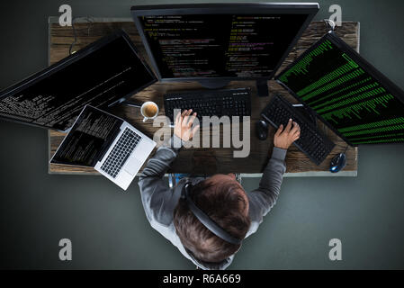 Hacker Hacking Multiple Computers On Desk Stock Photo