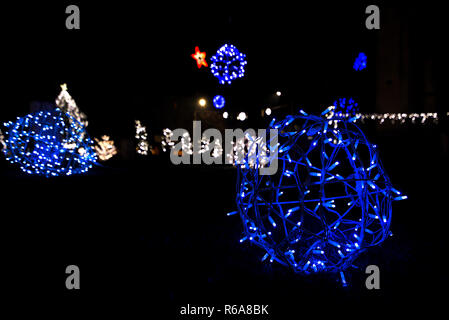 Glowing snowflakes and light stripes on dark, romantic night sky background. Beautiful Christmas market and decorations in city center. Stock Photo