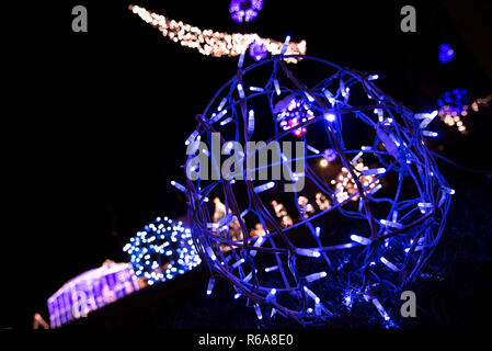 Glowing snowflakes and light stripes on dark, romantic night sky background. Beautiful Christmas market and decorations in city center. Stock Photo