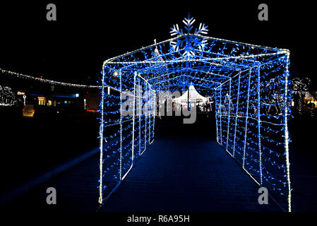 Glowing snowflakes and light stripes on dark, romantic night sky background. Beautiful Christmas market and decorations in city center. Stock Photo