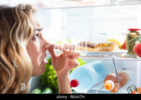 Young Woman Holding Her Nose Near Foul Food Stock Photo