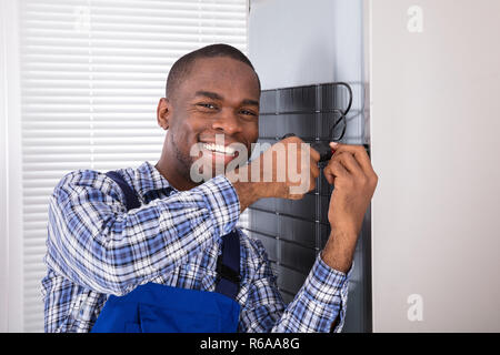 Serviceman In Overall Working On Fridge Stock Photo