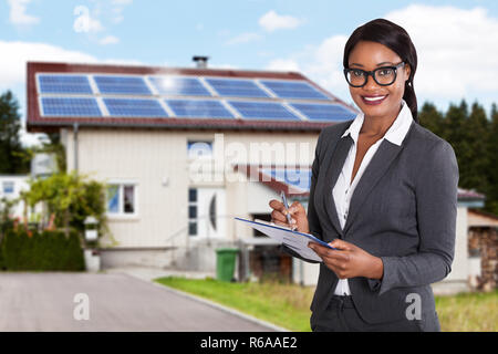 Businesswoman Filling Document In Front Of House Stock Photo