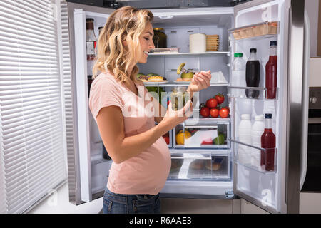 Pregnant Woman Eating Pickle From Jar Stock Photo