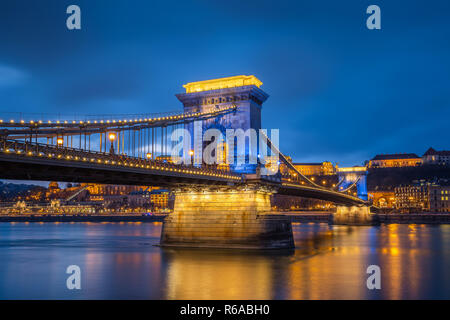 Budapest, Hungary - Beautiful Szechenyi Chain Bridge in unique blue colour with Buda Castle Royal Palace at background at dusk Stock Photo