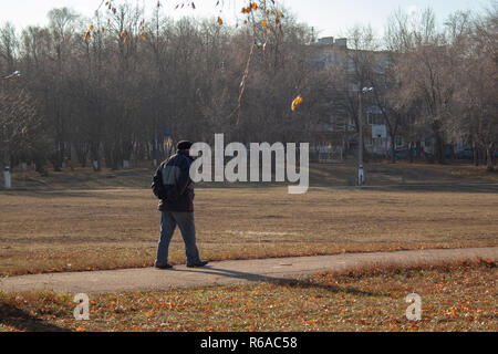 A lonely old man walks on a sunny autumn day. Stock Photo