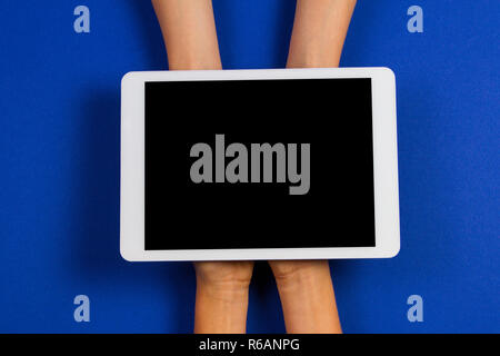 Two kid hands holding tablet computer over blue background Stock Photo