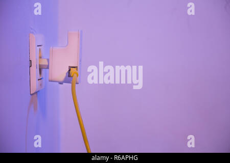 WiFi extender in electrical socket on the wall with ethernet cable plugged in Stock Photo