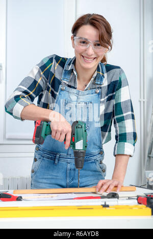 pretty young smiling woman using cordless drill Stock Photo