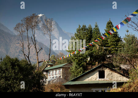 Nepal, Lukla, Chheplung, village houses below prayer flags and snow capped peak of Solu Khumbu Stock Photo