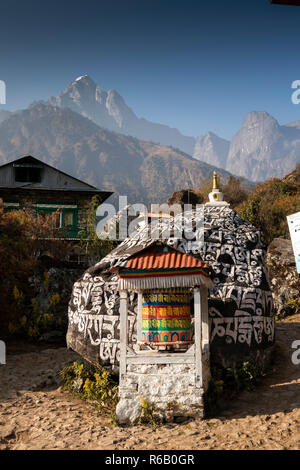 Nepal, Nurning, Buddhist prayer wheel and large mani stone on Everest Base Camp Trek path Stock Photo