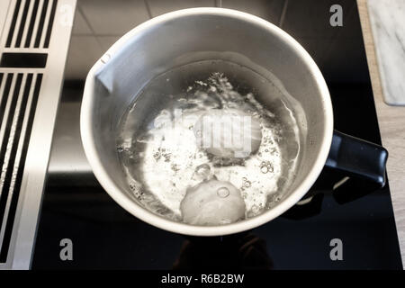 boiling eggs in a pot on a stove Stock Photo