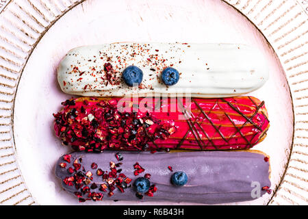 colorful eclairs red white violet with blueberry, raspberry, isolated on white background Stock Photo