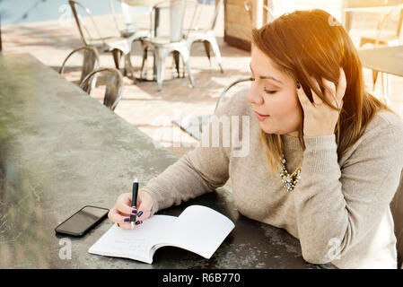 A young woman writes her 2019 New Years Resolutions in a journal Stock Photo