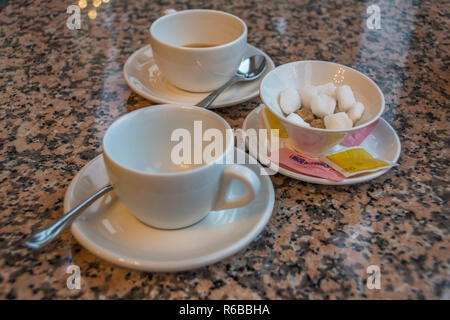 Two white cups of tea on saucers and a sugar bowl with sugar cubes. Stock Photo