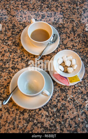Two white cups of tea on saucers and a sugar bowl with sugar cubes. Stock Photo