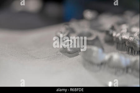 Object printed on metal 3d printer, laser sintering machine for metal close-up. A metal object sprinkled with metal powder after raising the platform into working chamber. DMLS, SLM, SLS technology. Stock Photo