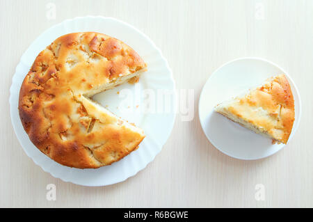 Sliced piece of cake on a white plate. Pie on the kitchen table. View from above. Stock Photo