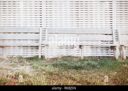 Bench stand at a wall from white colored boards at sunset by the sea Stock Photo
