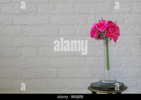 Pink roses in a glass vase isolated on a white brick wall, valentines day or interior background Stock Photo