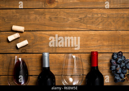 Glasses of wine bottles and grapes on wooden background. Top view with copy space. Stock Photo
