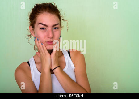 Close up of beautiful teenage girl touching both cheeks against  Stock Photo